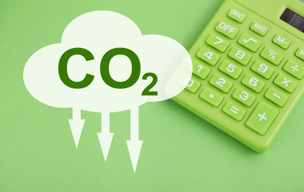 Imagen muestra una calculadora al costado de una nube con CO2 escrito para señalizar que es una calculadora de para medir la huella de carbono de cierta actividad.